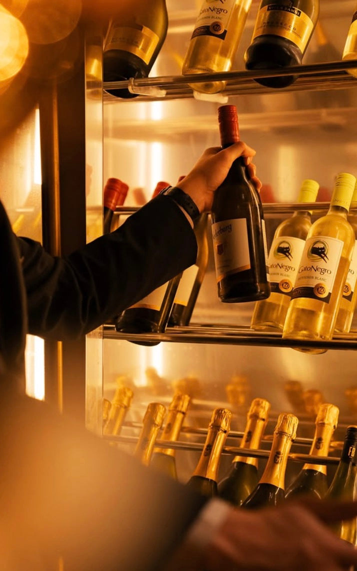 Main saisissant une bouteille dans une cave à vin dorée et rétroéclairée