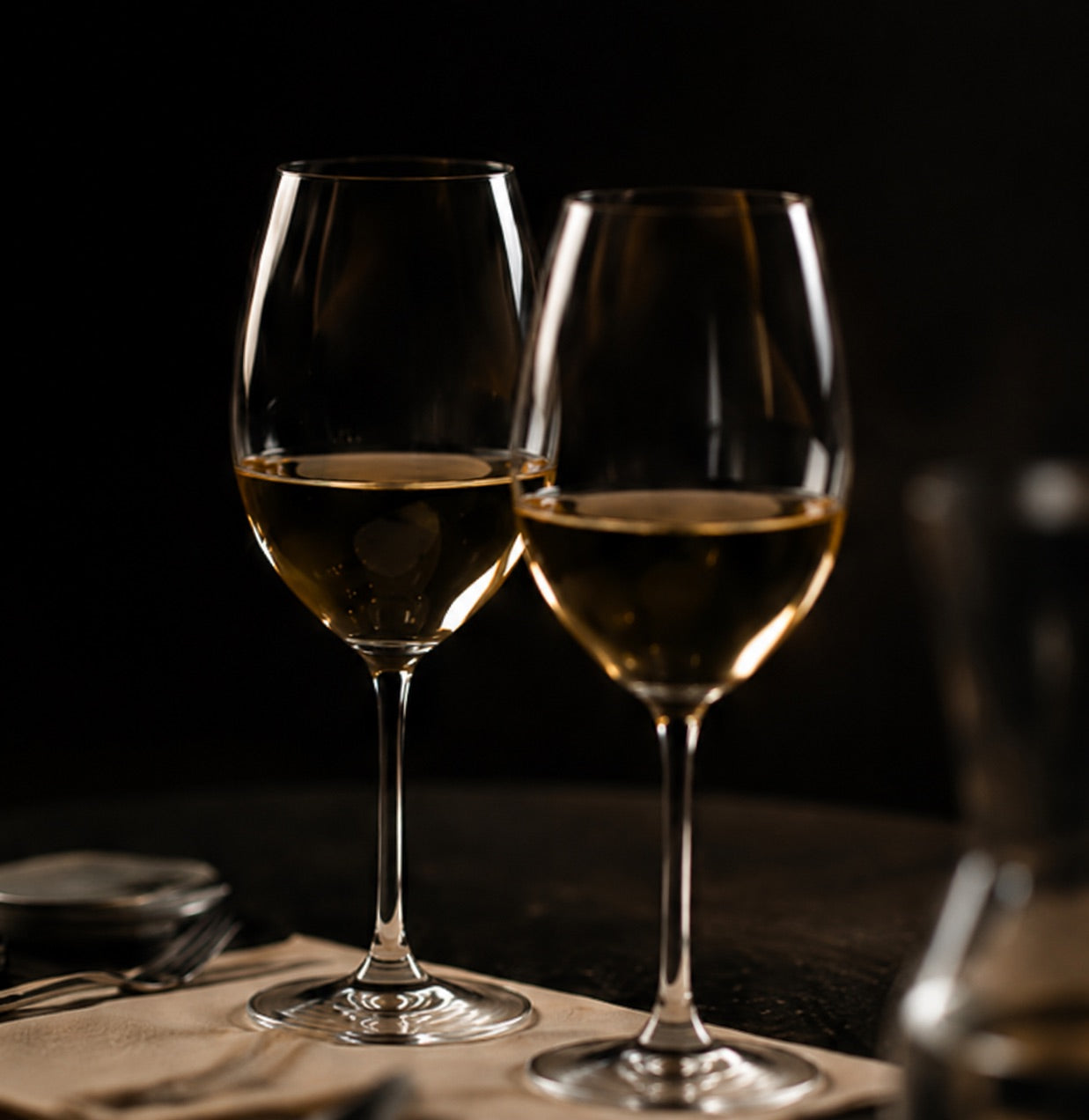 Deux verres de vin blanc sur une table sombre
