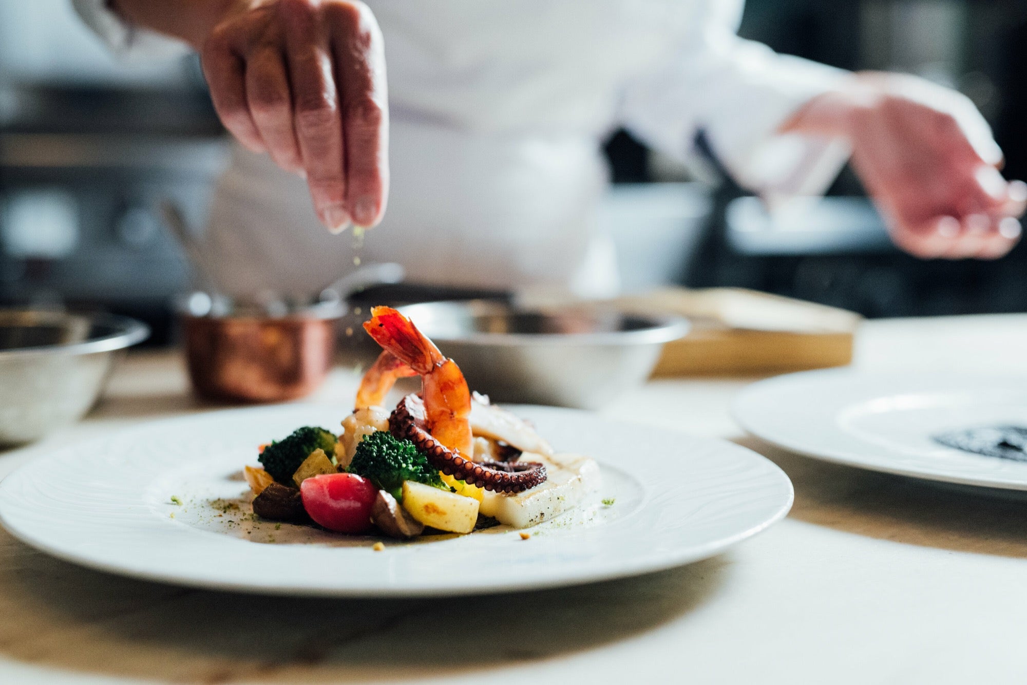 Le chef dresse l'assiette au passe, geste précis